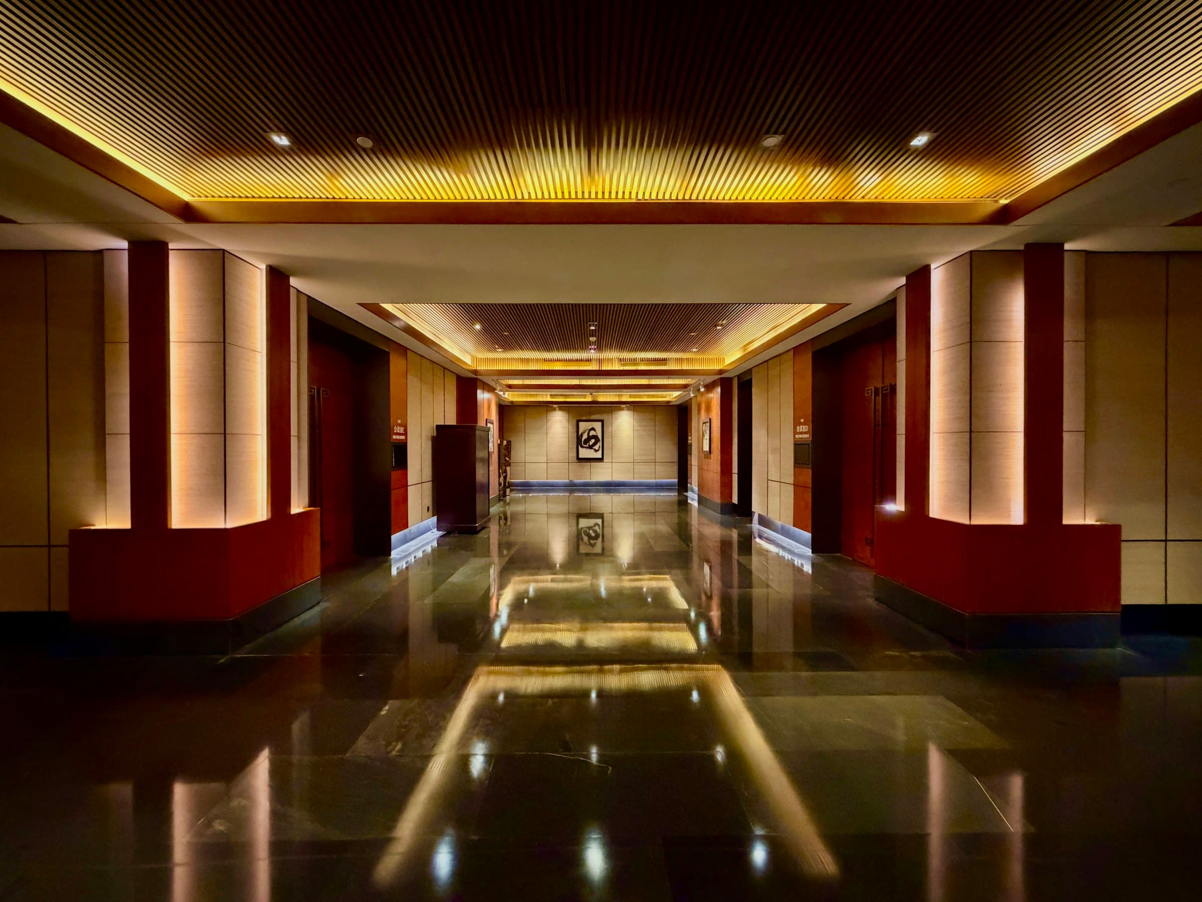 A luxury hotel corridor at night, warm light along a long hallway.