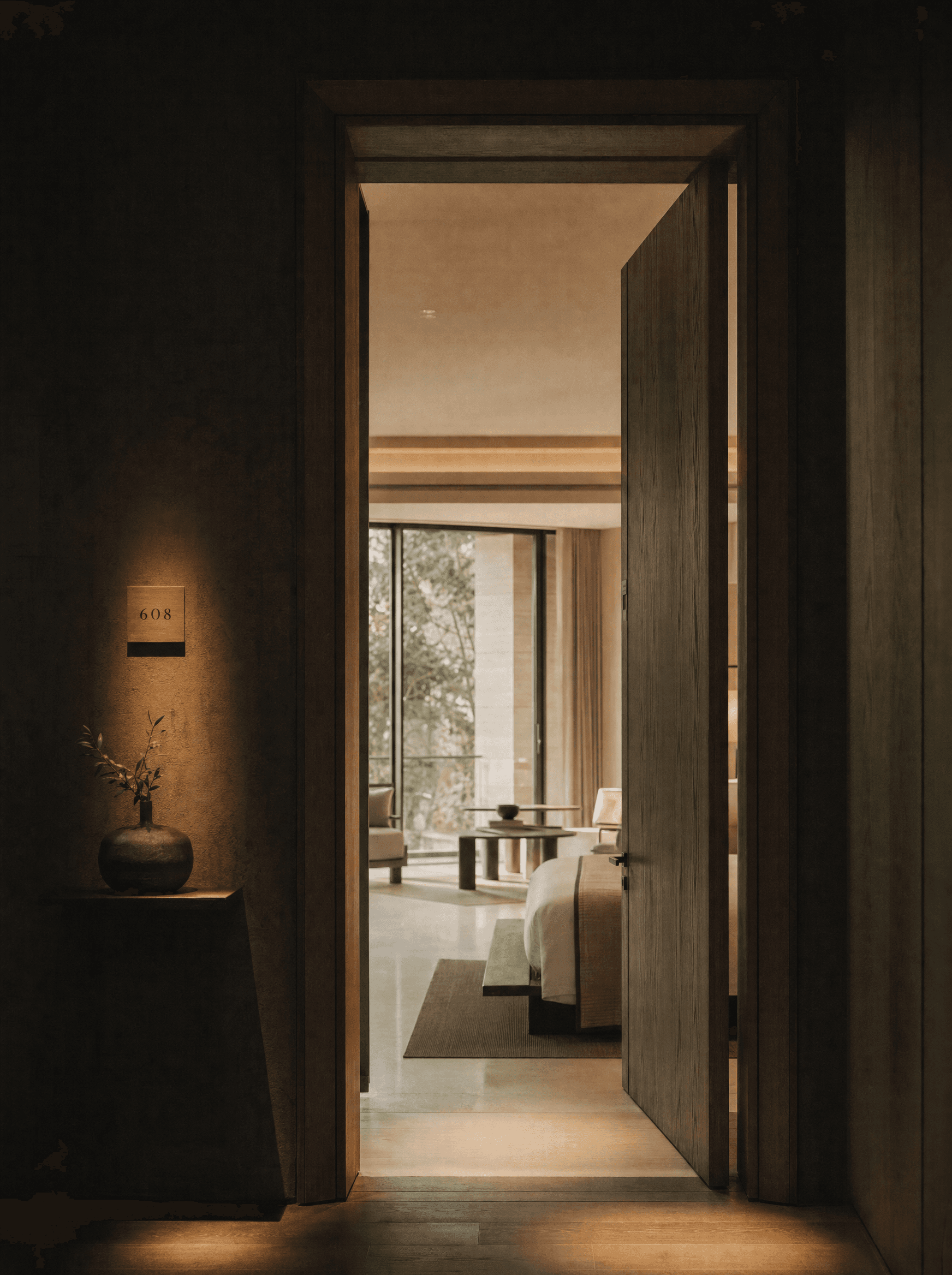 A door opening onto a more spacious hotel room beyond, warm light spilling through.