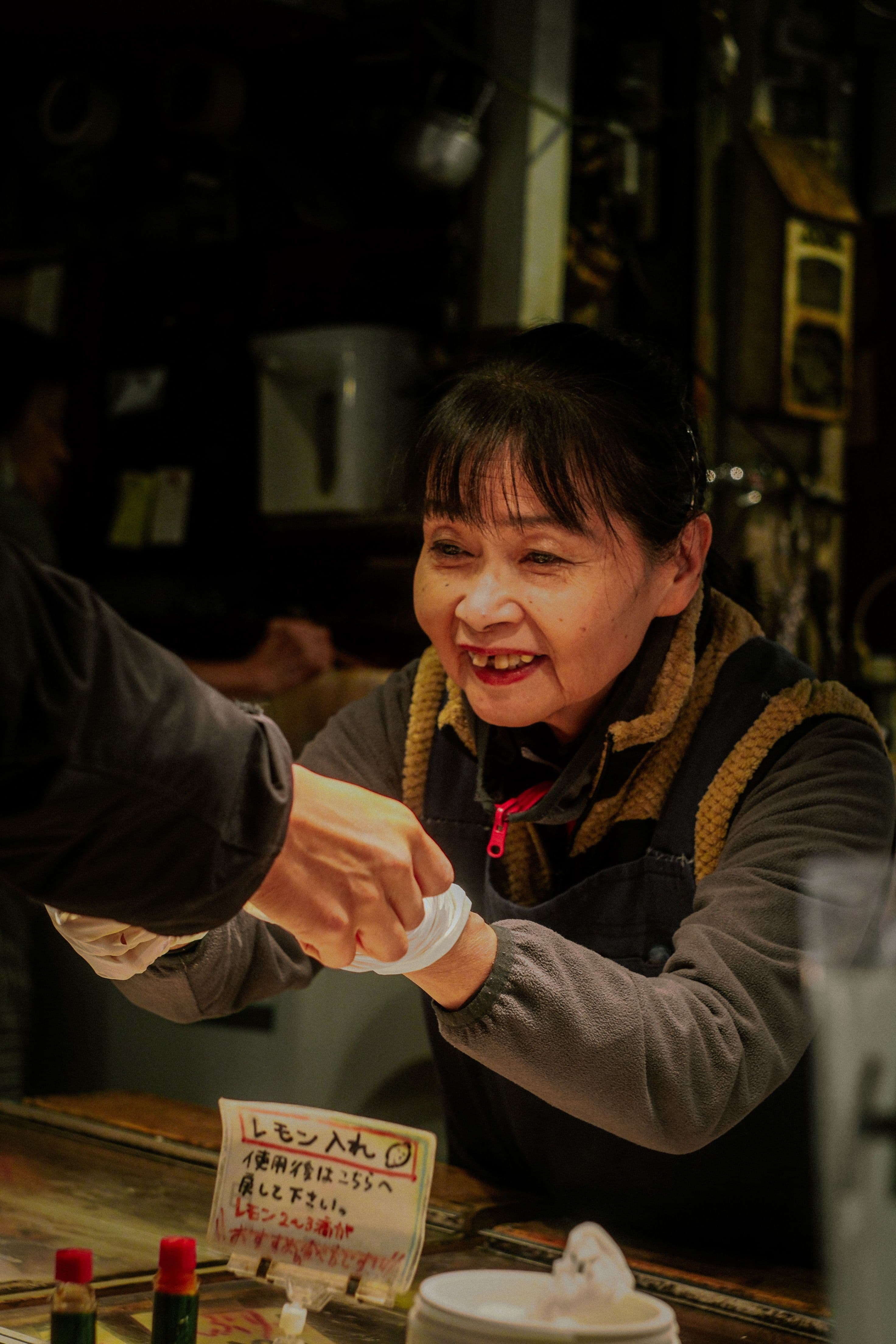 A market vendor’s hands passing a paper cup across the counter.